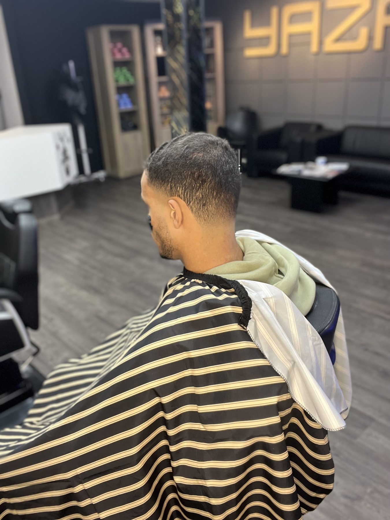 Een verse skin fade van achteren gezien, met de zwart-gouden kapmantel
